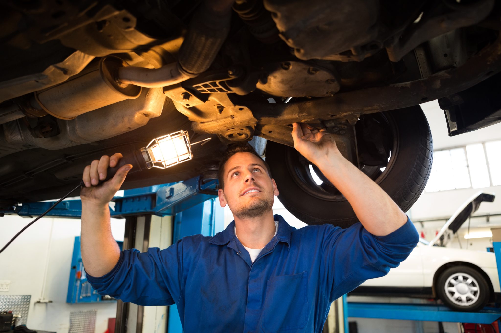 Mechanic Shining Torch Under Car At The Repair Garage
